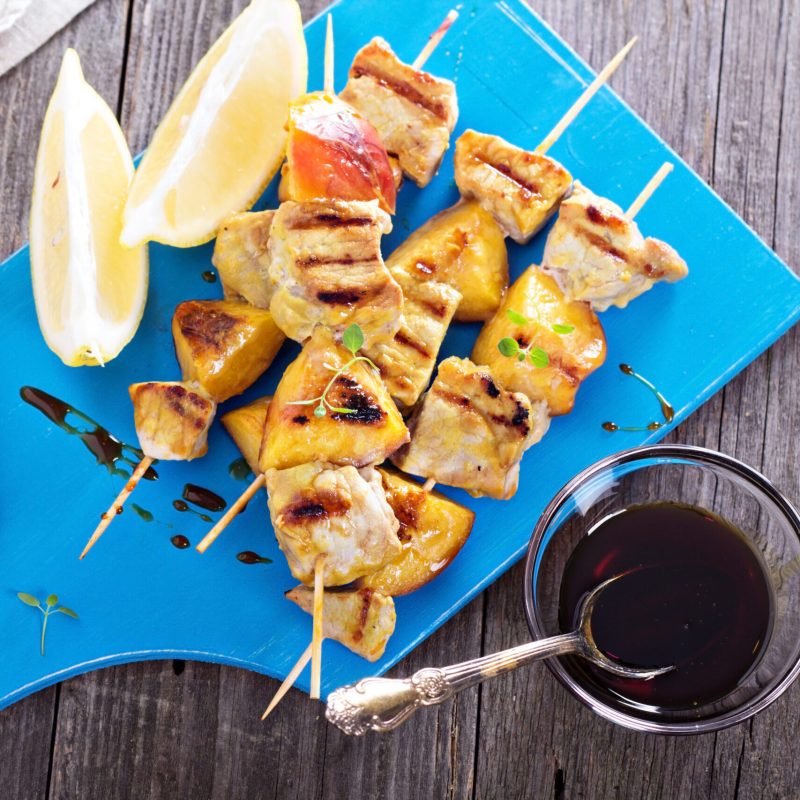 Grilled pork kabobs with peaches served on a cutting board