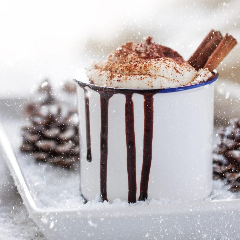 Dame-Blanche Homemade christmas hot chocolate with whipped cream, cacao and cinnamon on a plate in christmas holiday atmosphere